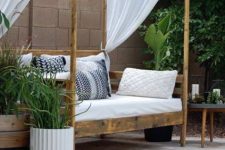 21 a simple stained canopy outdoor daybed with an arrangement of pillows, a canopy to protect from excessive sunlight and greenery around