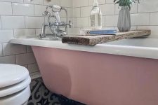 21 a small and pretty bathroom with a printed tile floor, a pink clawfoot bathtub, white subway tiles, greenery and white appliances