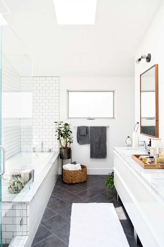 a Scandinavian bathroom with white and grey tiles, a basket for storage and potted plants
