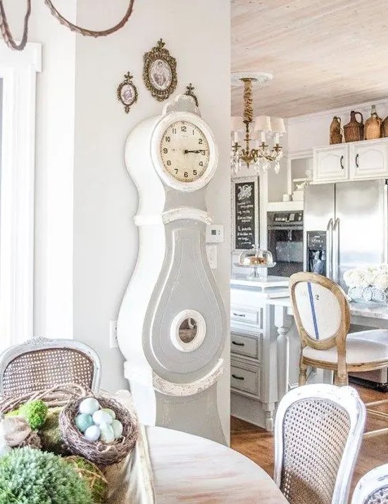a shabby farmhouse kitchen and dining space with a grandfather's clock in grey and white that matches the style of the space perfectly