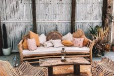 22 a simple rattan daybed with lots of muted color pillows is the main piece in this boho terrace