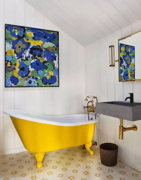 a small attic bathroom with white shiplap, a yellow clawfoot bathtub, a wall-mounted sink, a bright artwork and a mirror