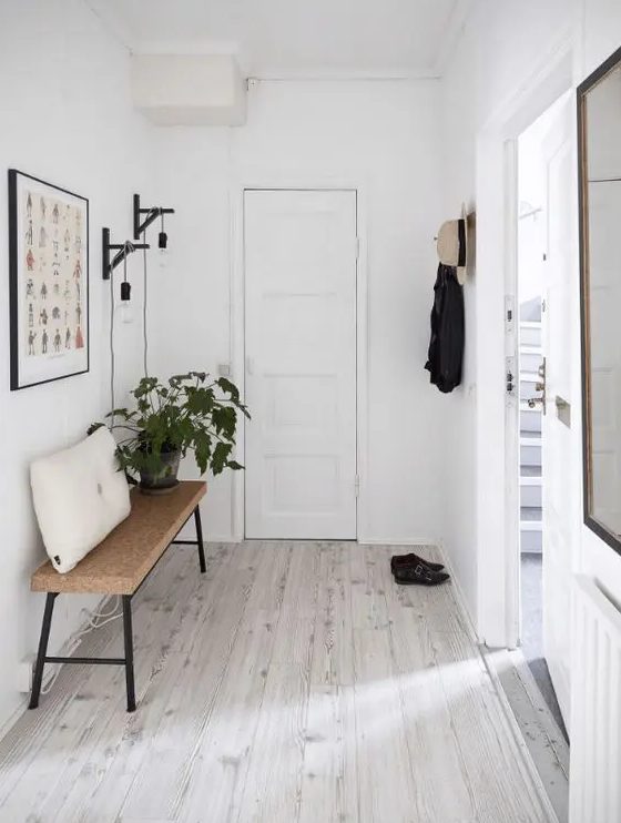 a Scandinavian entryway with whitewashed floors and a cork bench feels minimal and airy