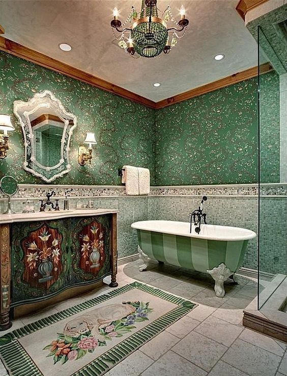 a unique green bathroom with botanical wallpaper, green tiles on the walls, a green striped clawfoot bathtub, an inlay vanity and a crystal chandelier