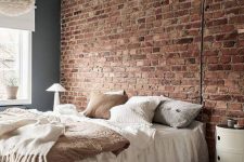 24 an exposed red brick wall as a statement in the room, neutral furniture, a fluffy pendant lamp and a cool nightstand