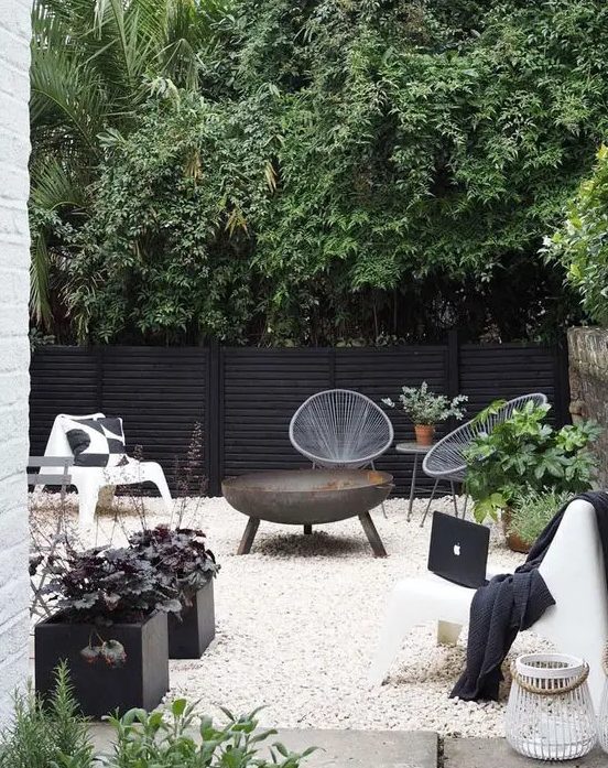 a Scandinavian terrace in black and white, with potted greenery and a fire bowl is a super stylish space that welcomes in