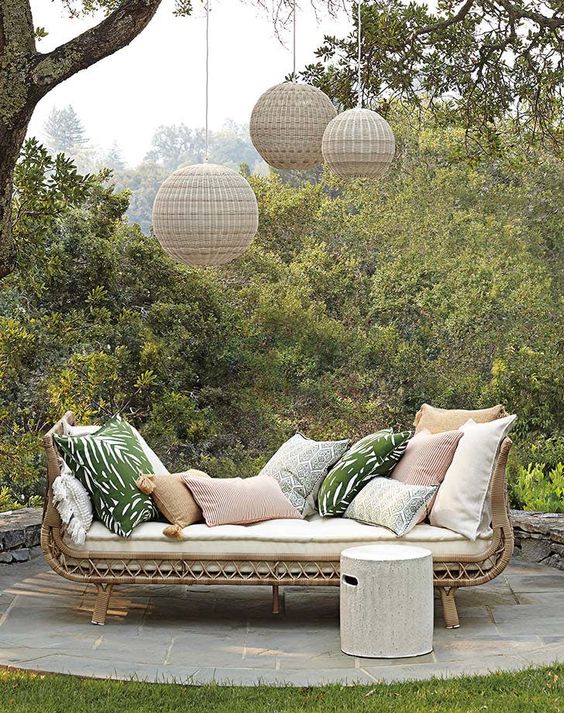 a rattan daybed with pastel and printed pillows, hanging woven pendant lamps and a side table is a lovely idea for outdoors