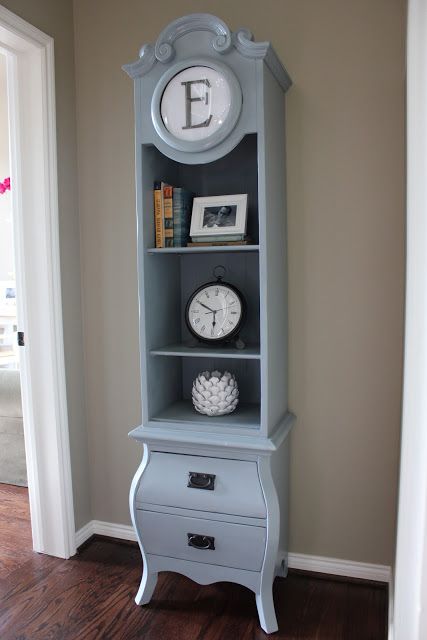 a light blue grandfather clock with open storage shelves with some decor and books plus a monogram is a stylish idea