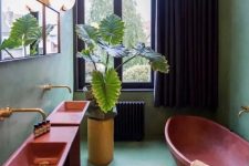 30 a green maximalist bathroom with red free-standing sinks, a red oval bathtub, a neutral rug, potted plants and a mirror, black curtains