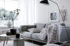 30 a stylish monochromatic Scandinavian living room with a grey sofa, neutral furniture, a black lamp and pots, neutral textiles is chic