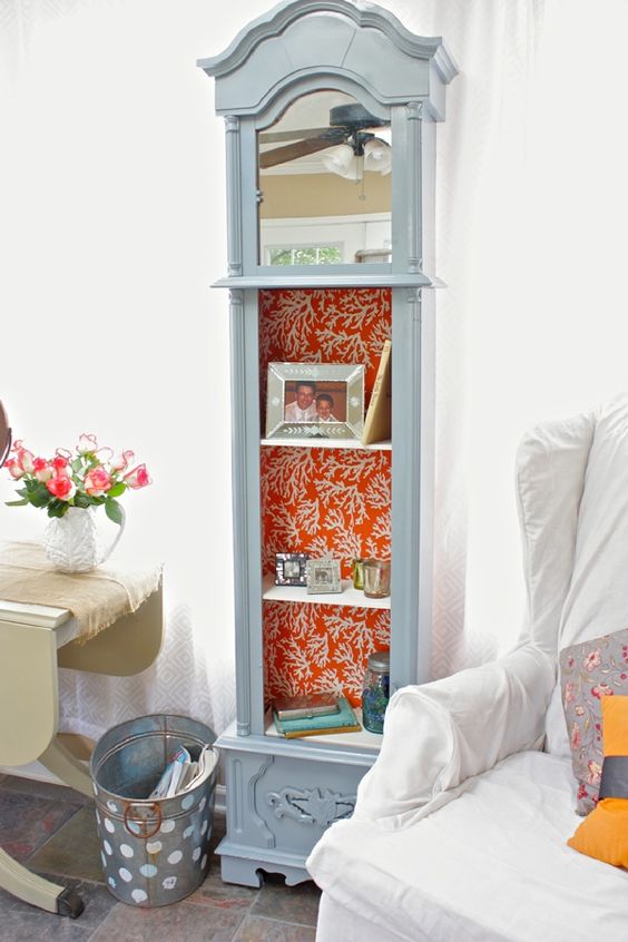 a serenity blue grandfather clock with orange coral print wallpaper as lining, with various decor and photos
