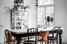 32 a vintage Nordic dining room with a vintage black dining table, mismatching chairs, a white glass cupboard and lots of potted plants