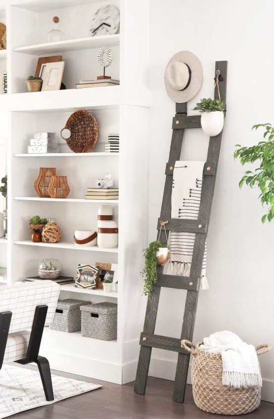 a grey ladder next to the shelving unit stores blankets, hanging greenery in pots and a hat on top