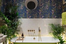 33 a stylish bathroom with botanical wallpaper, white subway and penny tiles, a neon green modenr tub, potted greenery and a vintage vanity