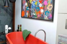 34 a super bold and catchy bathroom with a hot red free-standing bathtub, a bright artwork and black pendant lamps, small side tables and colorful towels
