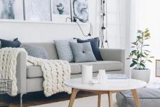 34 a welcoming Scandinavian living room with a grey sofa, blue pillows, a ledge with black and white artworks, a round table and a cushion on the floor