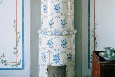 41 a traditional Scandinavian stove clad with blue and white printed tiles is a beautiful idea for a Nordic space, it will add both color and pattern