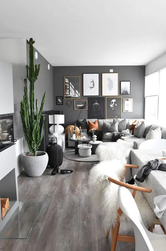 a beautiful Nordic living room with slate grey walls, a gallery wall, a grey sectional, a potted cactus and various lamps