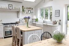 a beautiful attic cottage kitchen with shaker style cabinets, skylights, pendant lamps and a small kitchen island with woven stools