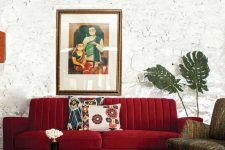 a beautiful living room with catchy walls, a deep red sofa, printed furniture and a rug and a vintage suitcase for storage