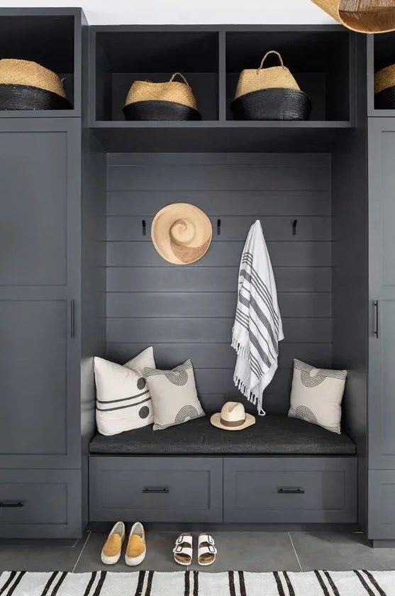 a beautiful slate grey mudroom unit with baskets, racks, drawers and cabinets for storage, striped textiles
