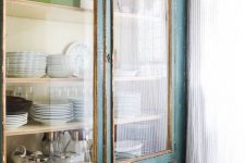 a beautiful teal and light-stained vintage cupboard with glass doors and drawers is a cool solution for storing dishes or other things