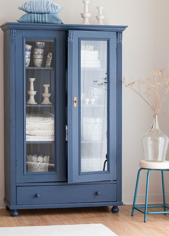a blue farmhouse vintage cabinet with glass doors and a drawer is a cool idea to display your items and to store them in a farmhouse space