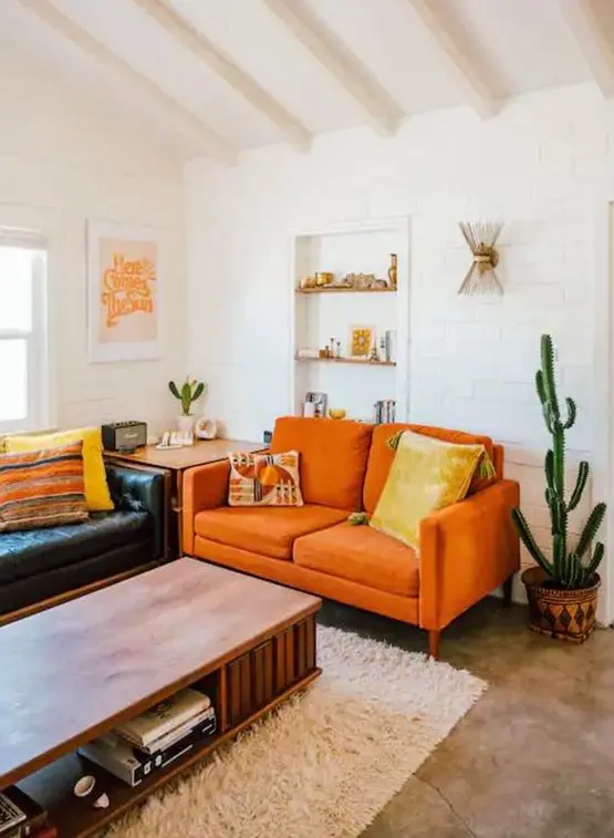 a boho living room with a black leather sofa, an orange loveseat, a low table and potted cacti feels warm and cool