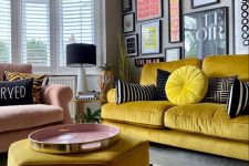 a bold and chic living room with grey walls, a yellow sofa and a pouf, a pink chair, a colorful gallery wall and a polka dot rug