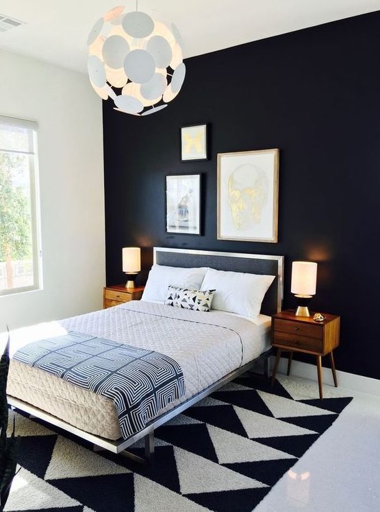 a bold and dramatic mid-century modern bedroom with a black statement wall, a geometric rug, a black bed and rich-stained nightstands