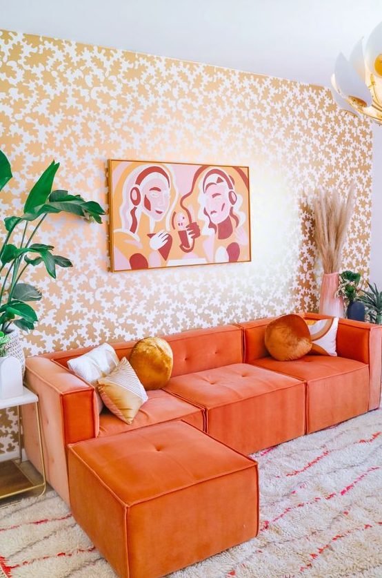 a bold living room with a botanical print wall, an orange sectional, a bold artwork and some plants and blooms