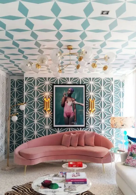 a bold living room with a printed ceiling and beautiful wallpaper, a pink curved sofa, round tables, a gold chandelier and bold art