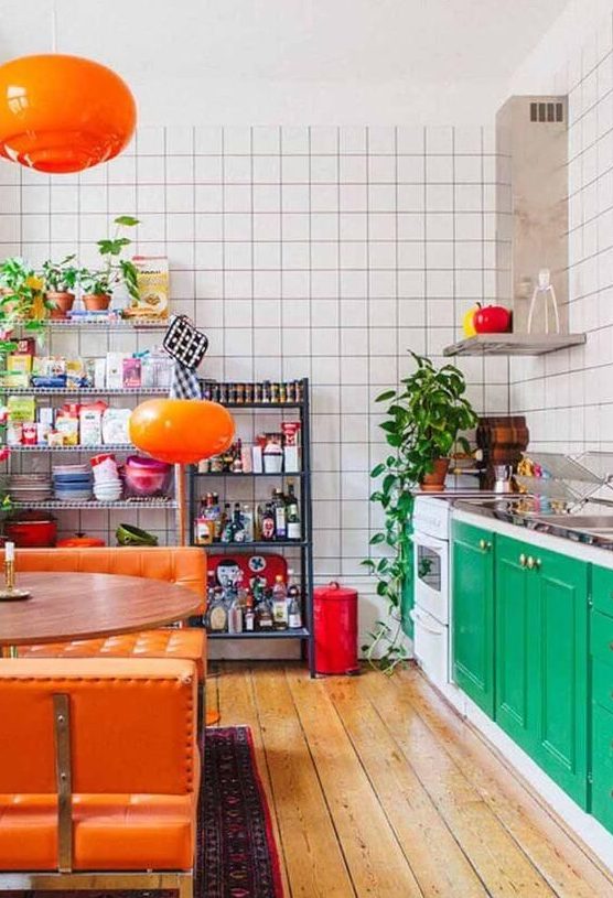 a bold maximalist kitchen with emerald cabinets, white tile walls, orange upholstered benches and lamps