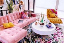 a bright living room with a pink sectional, a bold floral rug, a round coffee table, a mustard tufted chair, bright pillows and decor