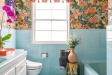 a bright maximalist bathroom with blue tiles and a bathtub, bright florla wallpaper, bold blooms and a sunbrust chandelier