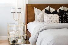 a bright mid-century modern bedroom with a rich stained bed, a white fluffy rug, a gilded frame nightstand and an abstract artwork