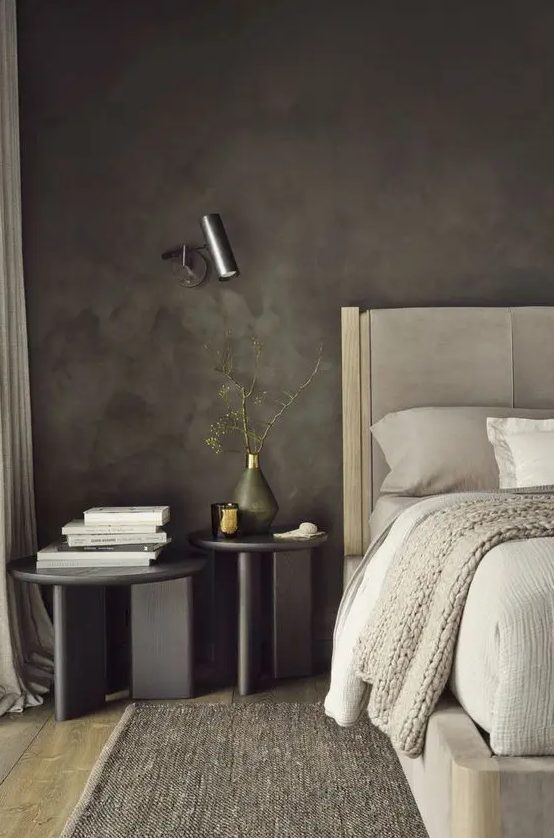 a chic contemporary bedroom with grey limewashed walls, a creamy bed and graphite grey nightstands and sconces