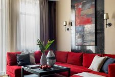 a chic contemporary living room with a red sectional, a bold artwork, pendant lamps, a black low table and various pillows
