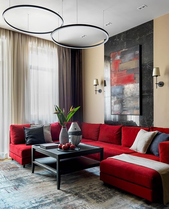 a chic contemporary living room with a red sectional, a bold artwork, pendant lamps, a black low table and various pillows