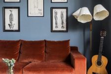 a chic living room with navy walls, a rust-colored sofa, a gallery wall , a floor lamp and low table with tiles is wow