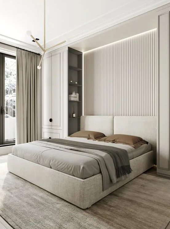a clean contemporary bedroom with a neutral slab accent wall, an upholstered bed, two tall storage units, built-in lights and pendant lamps