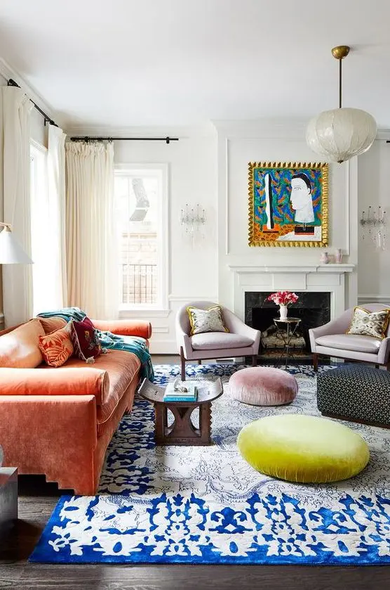 a colorful eclectic living room with a fireplace, lilac chairs, an orange sofa, Moroccan furniture, a rug and poufs is bold