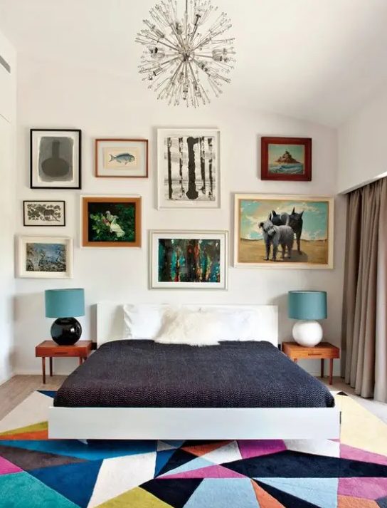 a colorful mid century modern bedroom with a bright geometric rug, a bed, laconic nightstands and an eclectic gallery wall