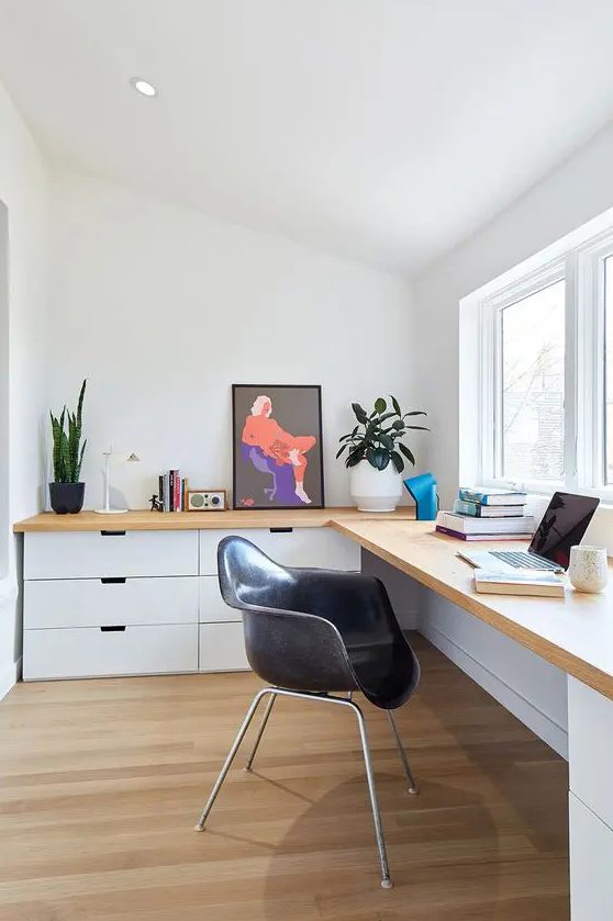 a contemporary home office with a large corner desk with lots of drawers,a small window and potted greenery is cool for working