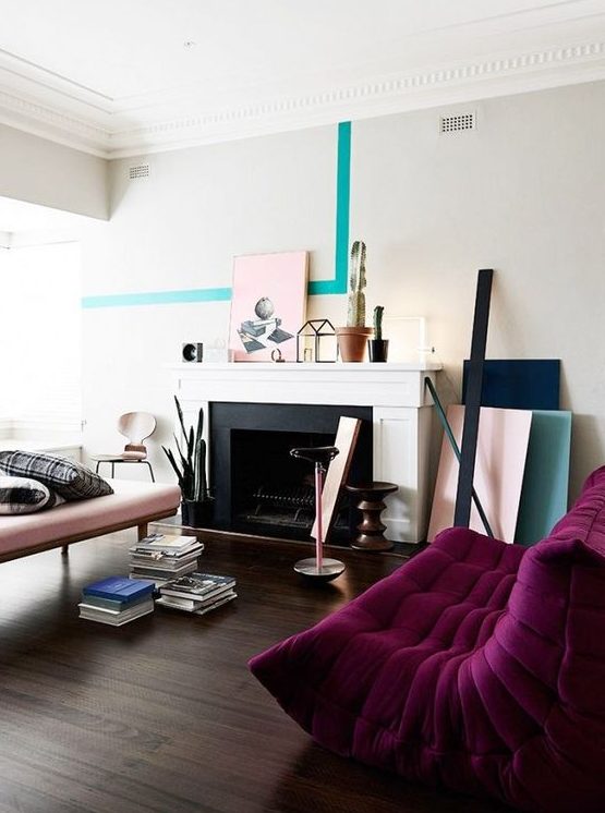 a contemporary living room with a non-working fireplace, a blush couch and a deep purple sofa, color blocking and books