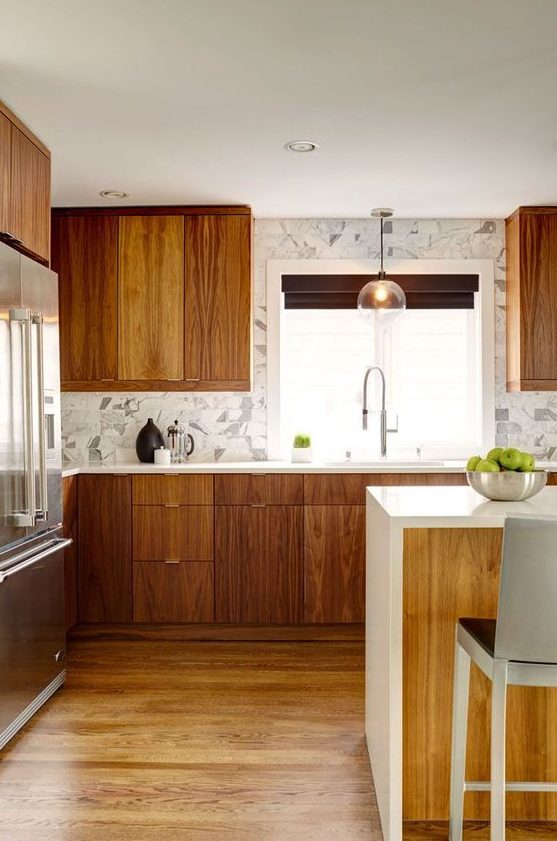 a contemporary meets mid-century modern kitchen with a marble tile backsplash, pendant lamps and a kitchen island with a waterfall top