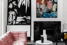 a contrasting living room with a black fireplace, a light pink sofa, a white coffee table, a black chair, pretty abstract artworks