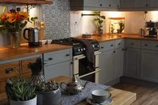 a cozy slate grey kitchen with shaker style cabinets, butcherblock countertops, a printed tile backsplash and an eatinп zone here