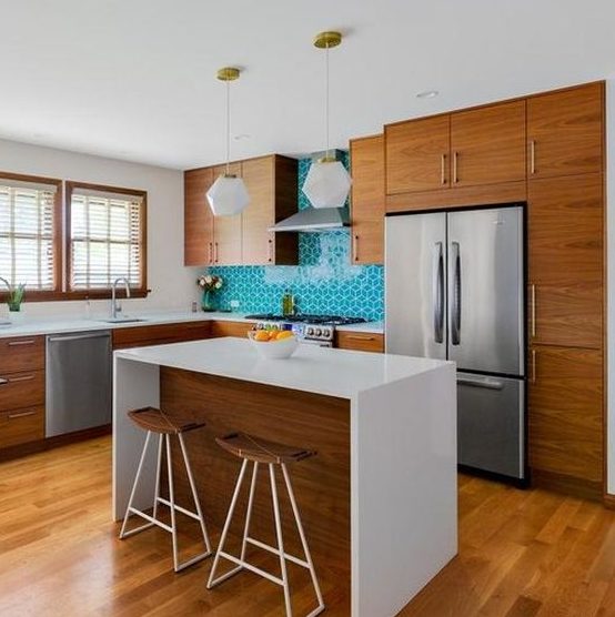 a cozy yet small mid century modern kitchen with rich stained cabinets, a turquoise tile backsplash, pendant lamps and a kitchen island