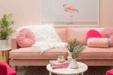 a glam living room with a pink sofa and pillows, hot pink chairs, a marble coffee table, a bright printed rug and potted greenery
